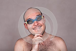 Funny man in swimming goggles daydreaming and looking at you