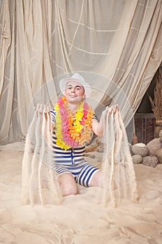 Funny man in vintage style striped swimsuit and colorful boa hold sand to sprinkle