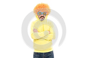 Funny man wear orange color wig with geeky look keep arms crossed, extravagant