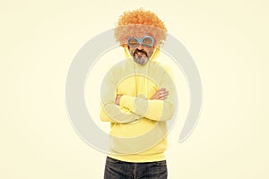 Funny man wear orange color wig with geeky look keep arms crossed, extravagant