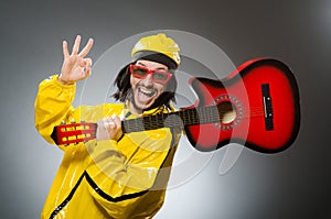 Funny man wearing yellow suit and playing guitar