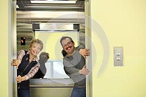 Funny man and woman hold door in an