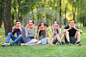 Funny men and women covering faces with tasty watermelon slices