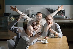 Funny millennial friends taking group selfie on smartphone in ca