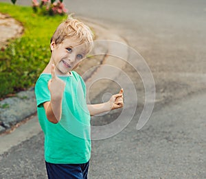 Funny mischievous cute boy make freckled face playing outside, laughing, show finger up. Behavior problems education