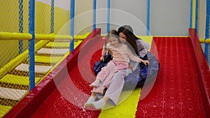 Funny mom and daughter sliding in a blue inflatable bun in amusment centre