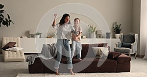 Funny mom and little daughter dancing fooling together at home