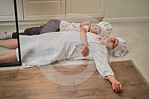 Funny mom and son relax in the kitchen after cooking. A tired woman and a boy are lying on the kitchen floor