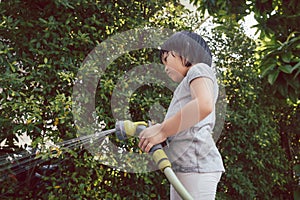 Funny moment of 3 Year old asian kid playing water with garden hose in backyard.