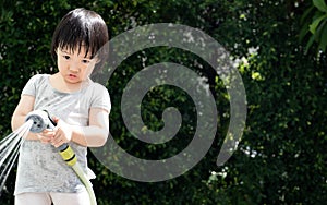 Funny moment of 3 Year old asian kid playing water with garden hose in backyard.
