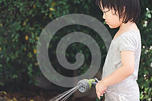 Funny moment of 3 Year old asian kid playing water with garden hose in backyard.