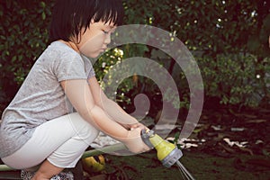 Funny moment of 3 Year old asian kid playing water with garden hose in backyard.