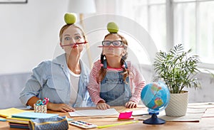 funny mother and child daughter doing homework writing and reading