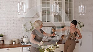 Funny mother and daughter arrange dueling with kitchen appliances in kitchen.