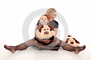 Funny Mother and daughter in same outfits posing with soft fluffy dog toy in the studio on the white background