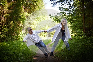 Funny mother with dreadlocks and fat boy happy walking in the woods on a sunny summer day