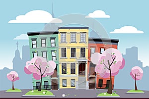 Funny multi-colored low city apartment buildings on the background of a big city. In front of the houses are blooming spring trees