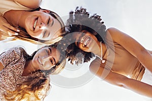 Funny multiracial smiling teenager gilrs standing and looking down at camera