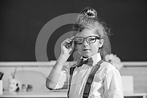 Funny nerd girl. Close-up portrait of merd girl in glasses in class room indoors. Little funny school girl face. Back to