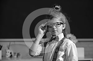 Funny nerd girl. Close-up portrait of merd girl in glasses in class room indoors. Little funny school girl face. Back to