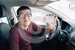 Funny nerd in huge ridiculous glasses shows his driver`s license. Concept of vision correction and fools on the road