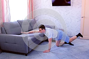 Funny nerd man is doing balance pose on all fours at home. Sport humor concept.