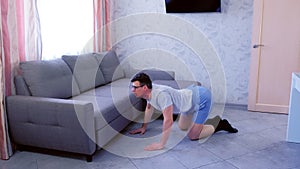 Funny nerd man is doing stretching rotating exercise for back standing on all fours at home. Sport humor concept.