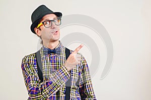 Funny nerd pointing finger away at copy space. Smiling young nerdy in glasses showing your product. Nerd man in plaid shirt and