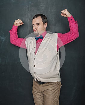 Funny nerd vintage style man flexing his muscle on blackboard