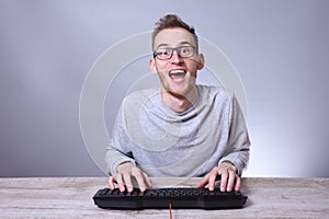 Funny nerd young businessman, man working on computer.Typing on the keyboard programmer in glasses in front of computer