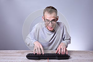 Funny nerd young businessman, man working on computer.Typing on the keyboard programmer in glasses in front of computer