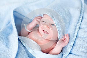 Funny newborn baby covered in blue bath towel