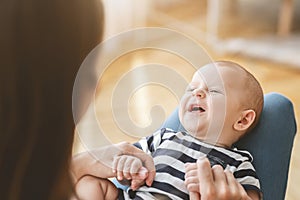 Funny newborn baby laughing while lying on mother`s lap