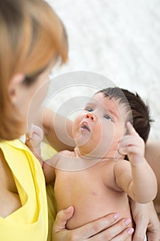 Funny newborn baby and mother looking each at other