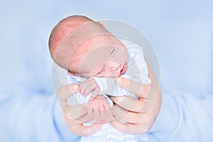 Funny newborn baby sleeping in his father's hands