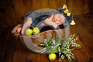 Funny newborn little baby girl in a costume of hedgehog sleeping sweetly on the stump