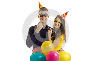 Funny nice guy and girl holding paper glasses a lot of colored balloons and smiling