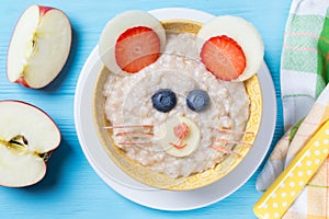 Funny oat porridge with mouse face made of fruits and berries, food for kids idea, top view