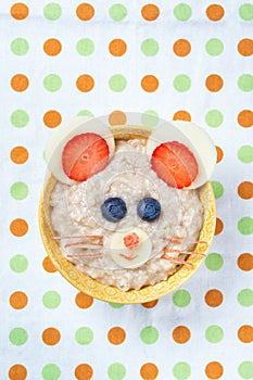 Funny oat porridge with mouse face made of fruits and berries, food for kids idea, top view