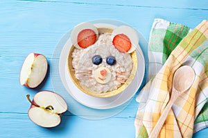 Funny oat porridge with mouse face made of fruits and berries, food for kids idea, top view