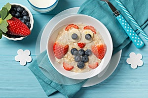 Funny oat porridge with owl face made of berries, food for kids idea, top view