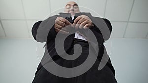 Funny obese man in classic suit fastening a button on his jacket, overweight