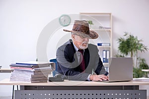 Funny old boss in cowboy hat in the office