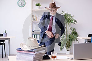 Funny old boss in cowboy hat in the office