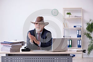 Funny old boss in cowboy hat in the office