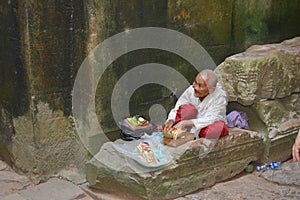 Funny old man seated in angkor wat temple,