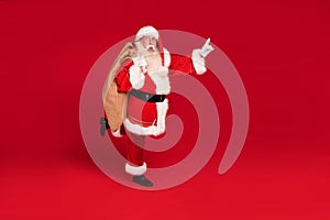 Funny old Santa Claus on a red studio background. Merry Christmas and Happy New Year! Copy space. Xmas sale, discount concept