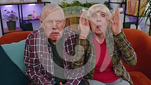 Funny old senior man woman making playful silly facial expressions, fooling around, showing tongue