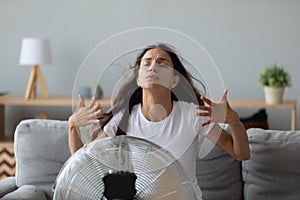 Funny overheated woman enjoying fresh air, cooling by electric fan photo