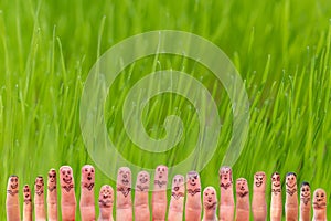 Funny painted fingers symbolizing a team against green background with grass